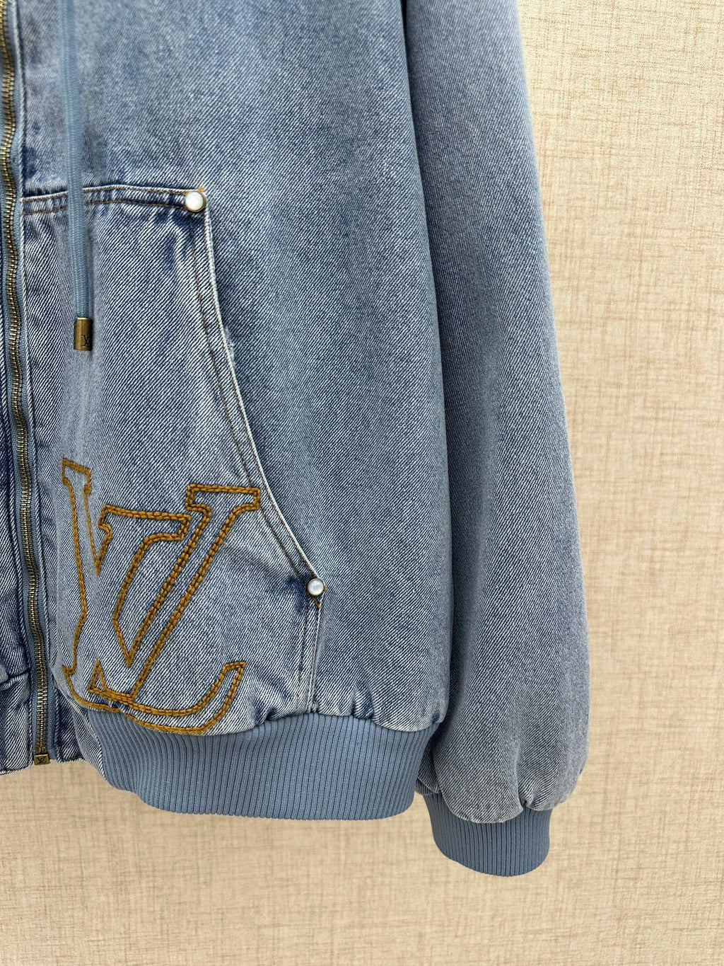 Light blue denim jacket pocket with gold LV embroidery and snap button