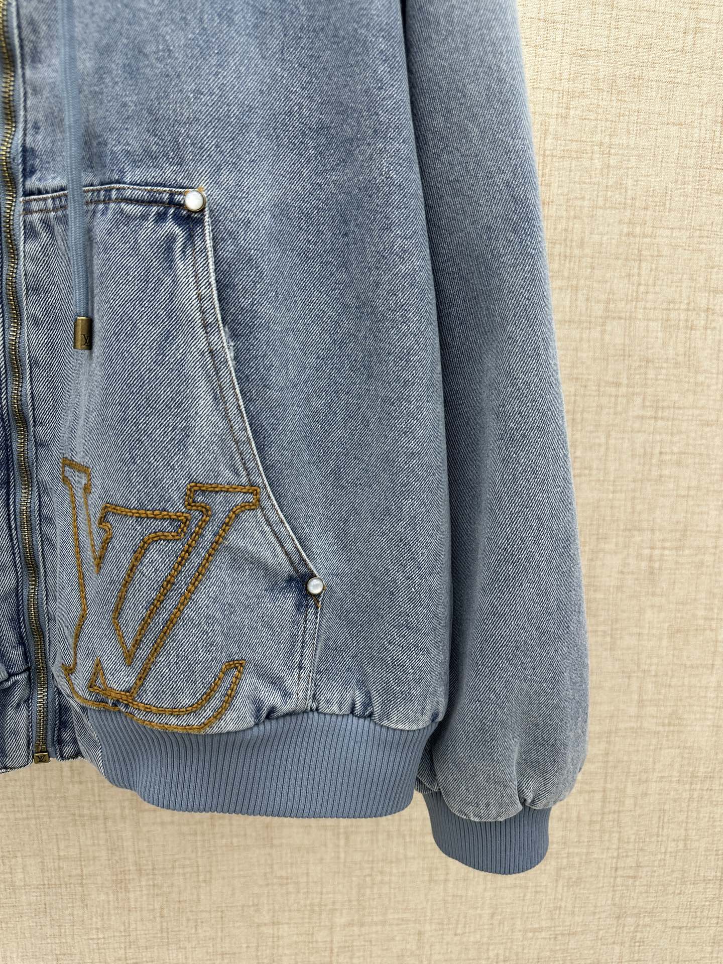 Light blue denim jacket pocket with gold LV embroidery and snap button
