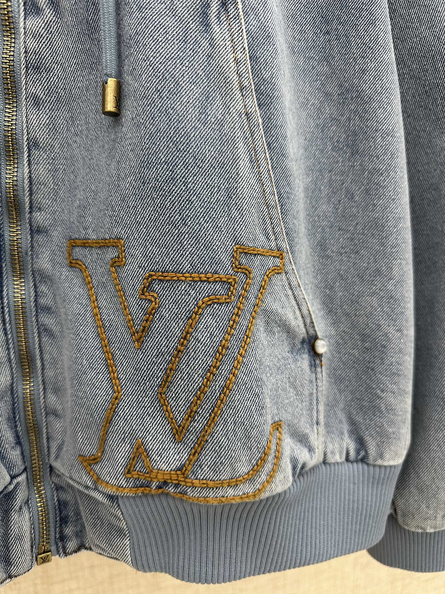 Light blue denim jacket lower front with large gold LV embroidery and ribbed hem