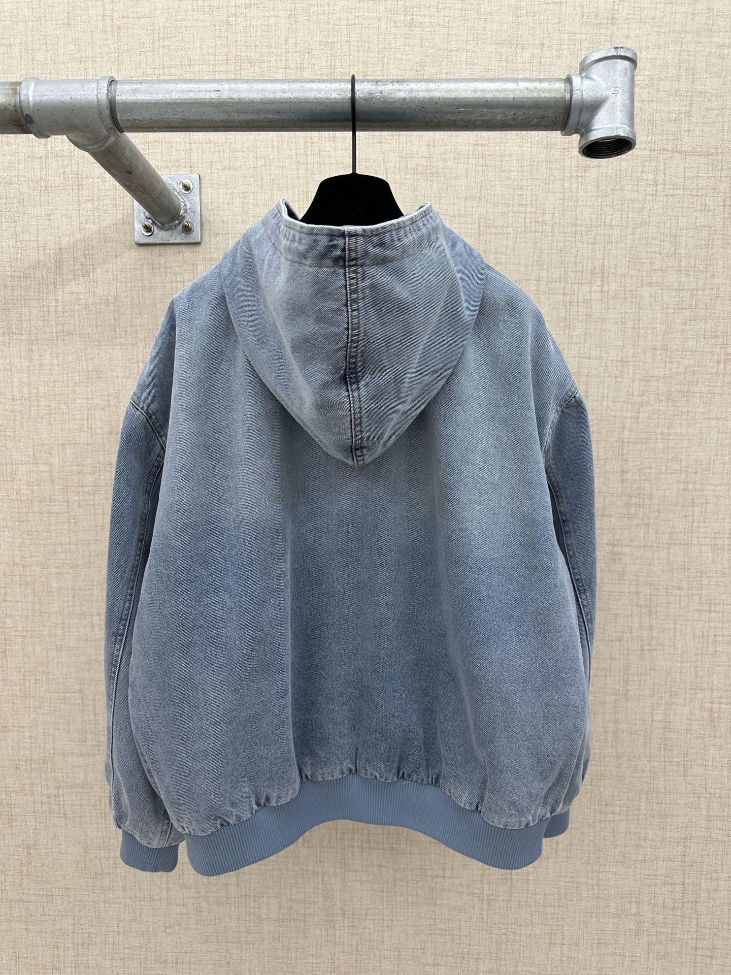 Light blue denim zip-up hoodie jacket with hood and logo print, back view