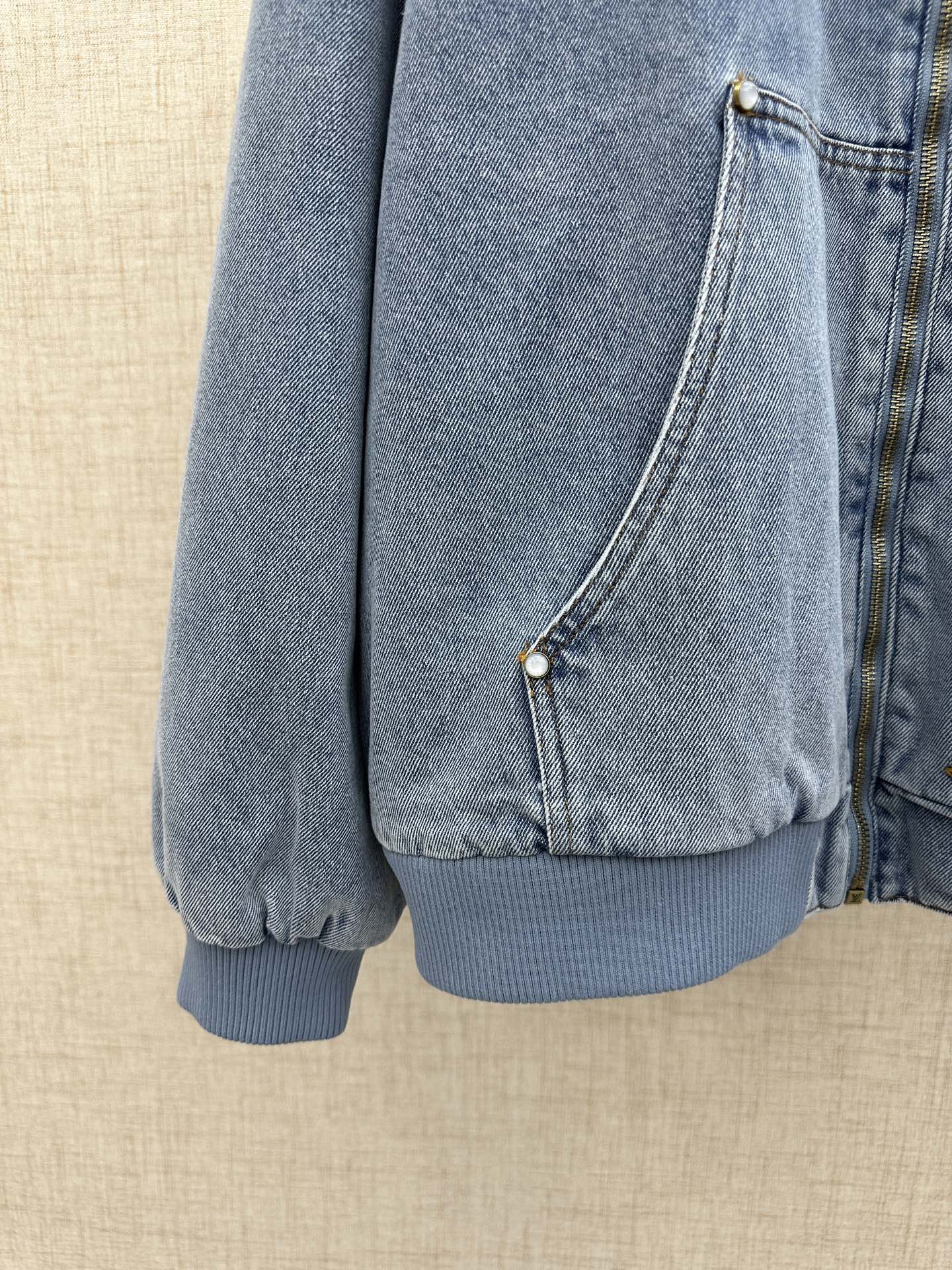 Light blue denim jacket front pocket panel with snap closure and ribbed cuff