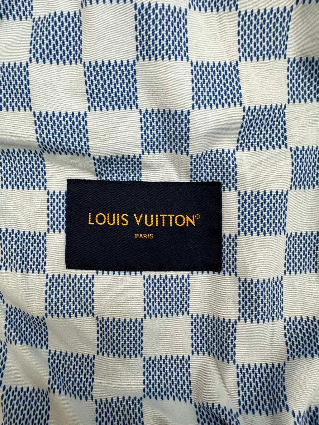 Louis Vuitton black fabric label with gold text on denim jacket