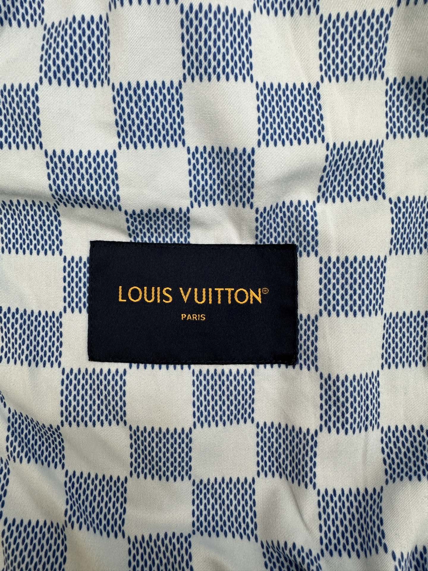 Louis Vuitton black fabric label with gold text on denim jacket