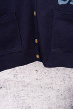 Navy cardigan front placket with gold button row and side pockets