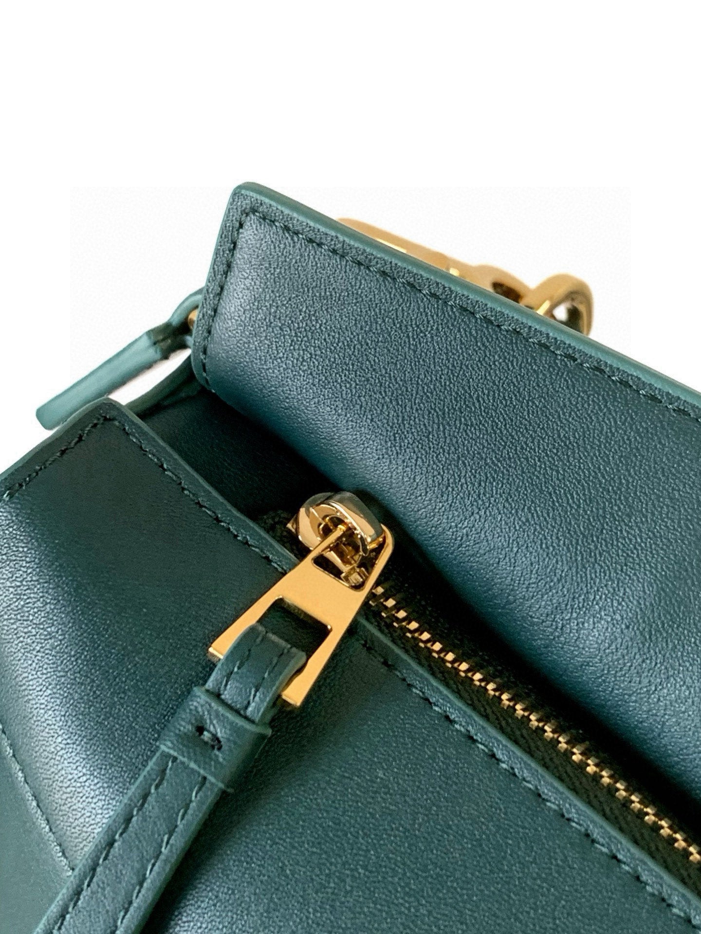 Teal leather bag corner detail with gold zipper pull and stitched trim