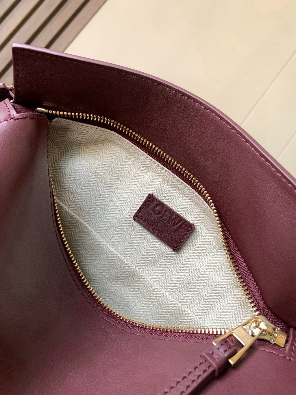 Inside view of burgundy Loewe bag showing fabric lining and zip pocket with label