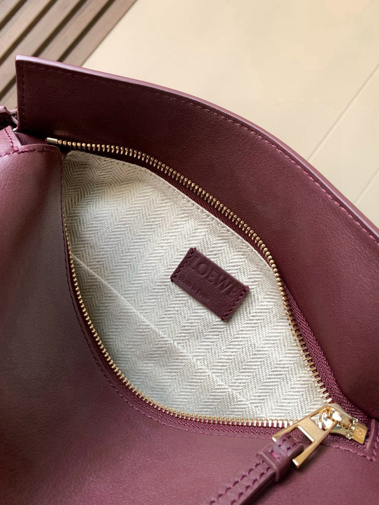 Loewe burgundy leather bag interior with striped lining and gold zip closure