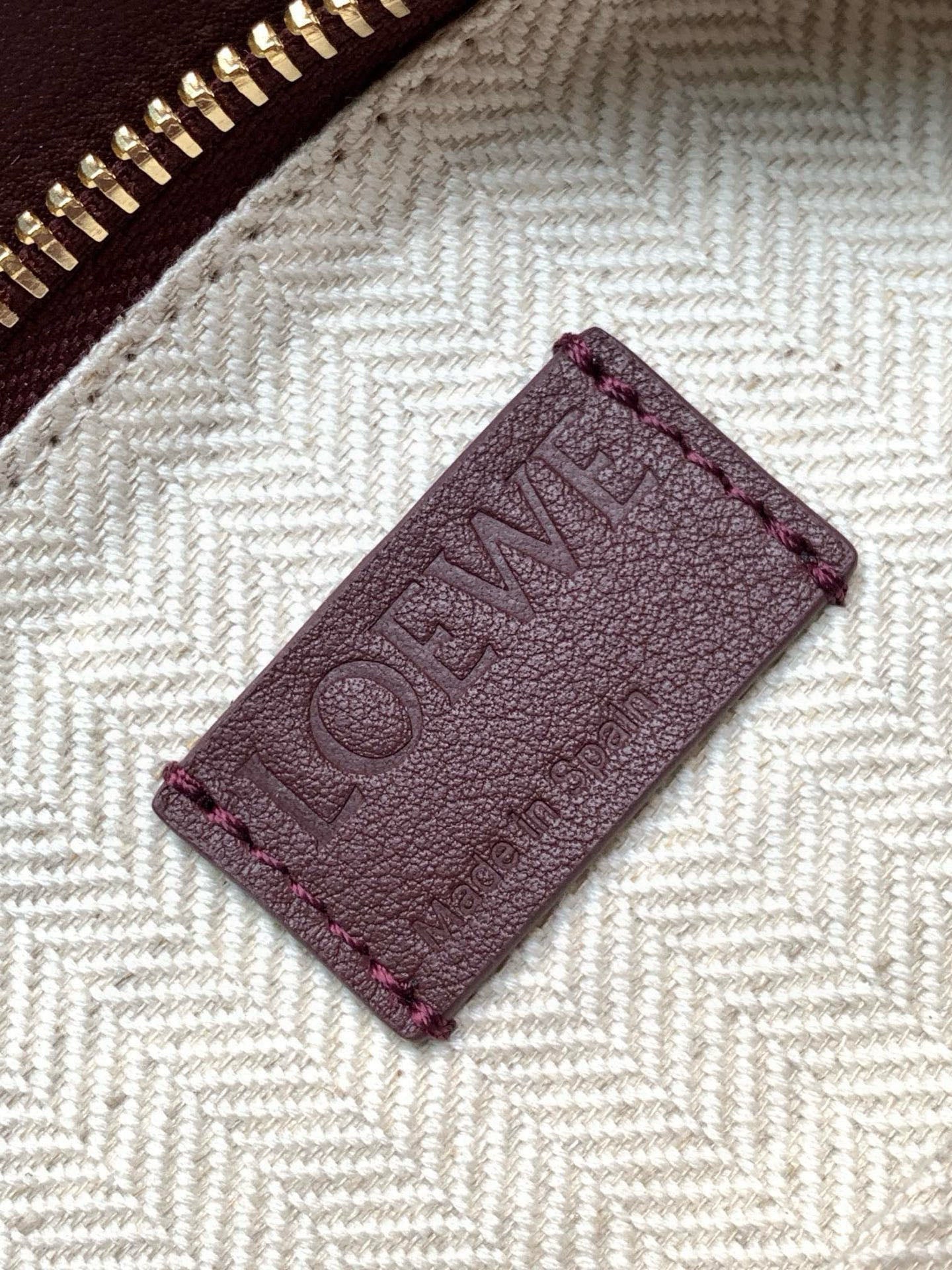 Close-up of burgundy leather Loewe logo patch inside the bag lining