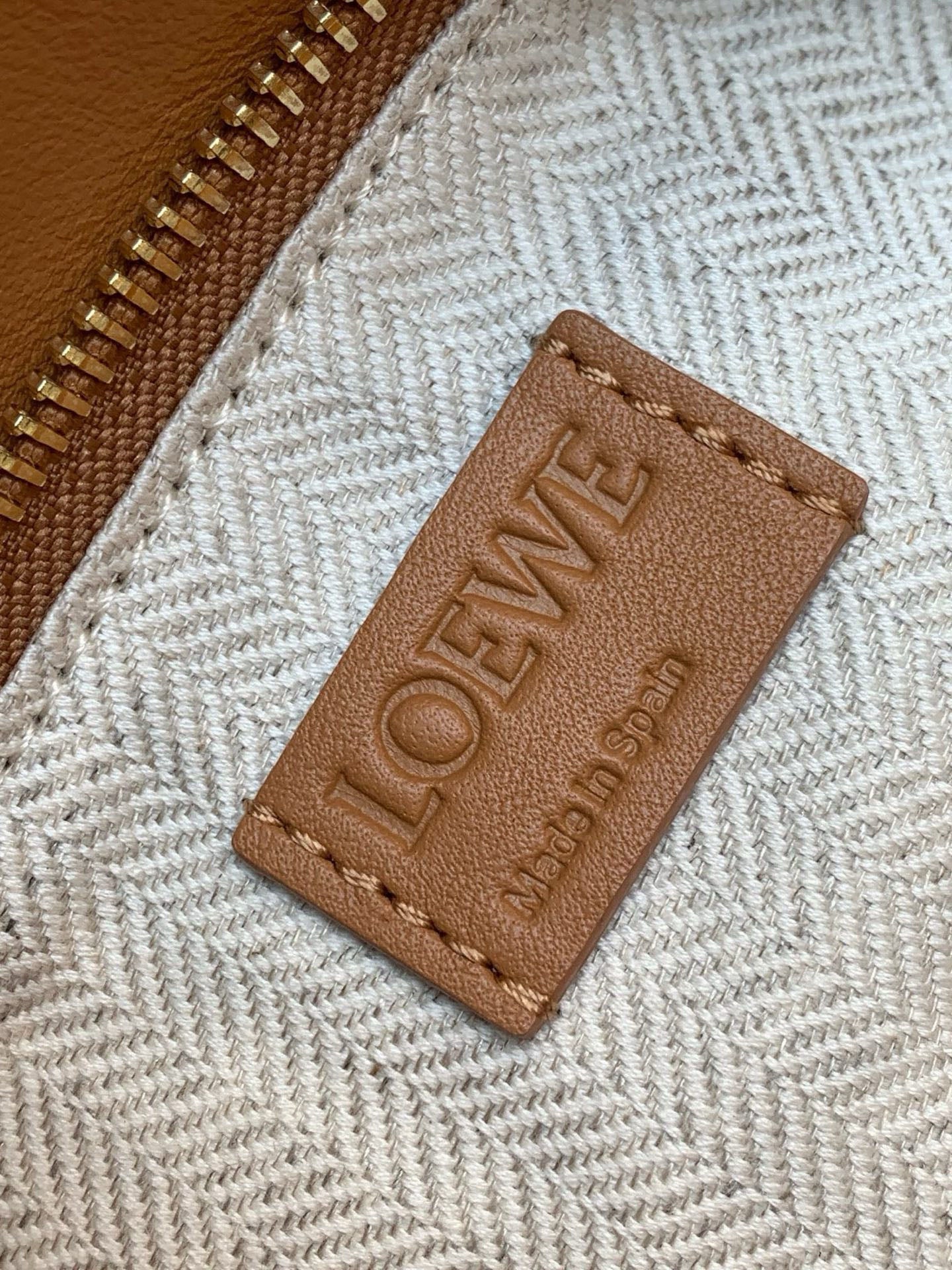 Loewe woven fabric lining with tan leather logo patch near zipper