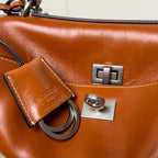 Balenciaga leather bag close-up with metal clasp, stitched strap tag, and engraved logo plate