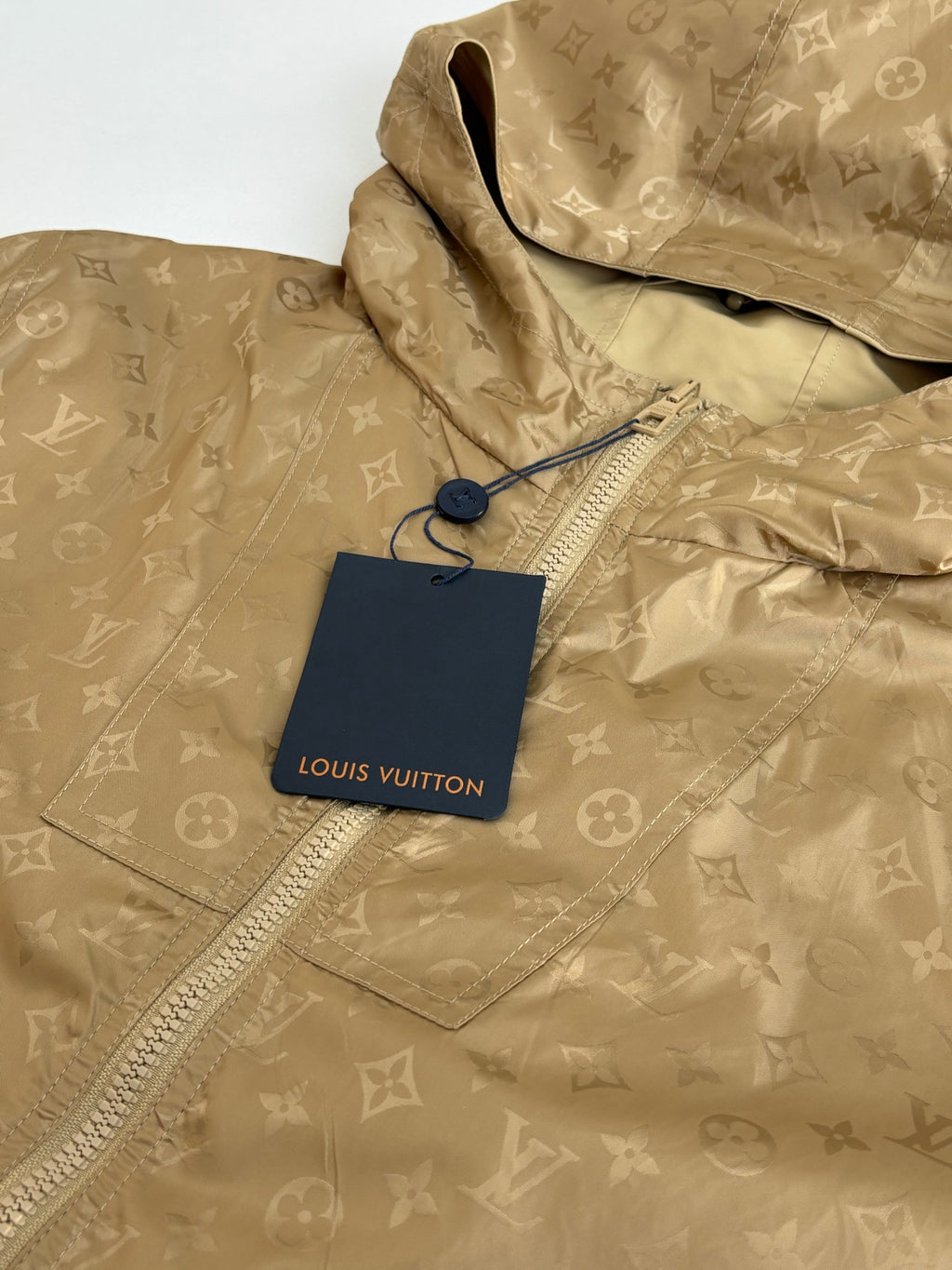 Louis Vuitton tan hooded jacket close-up with repeating monogram pattern and hang tag