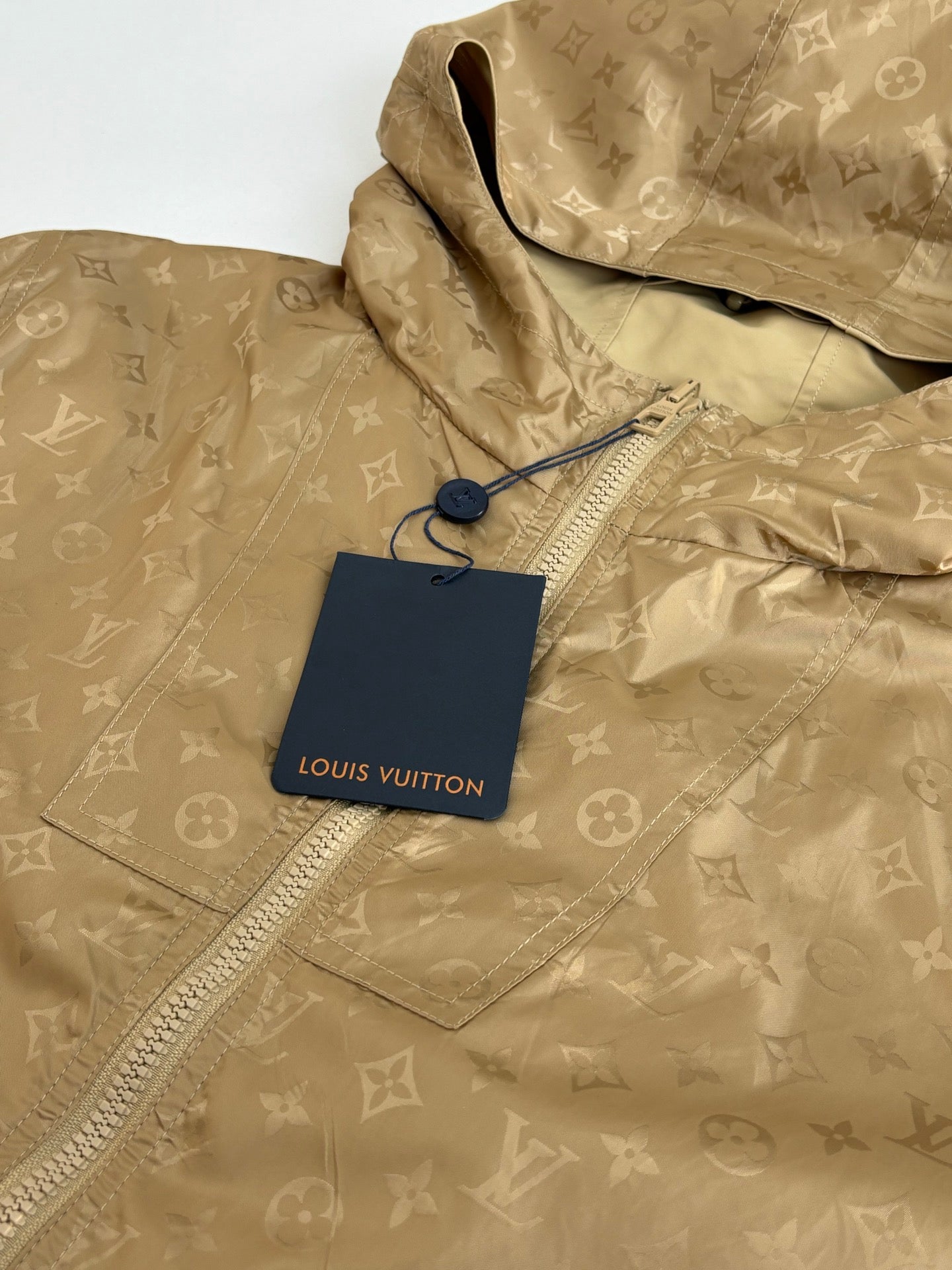 Louis Vuitton tan hooded jacket close-up with repeating monogram pattern and hang tag