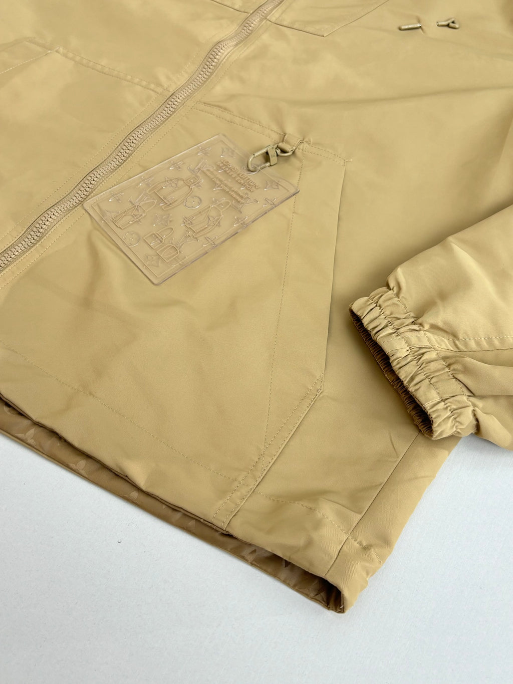 Beige long pants with embossed logo patch on front pocket
