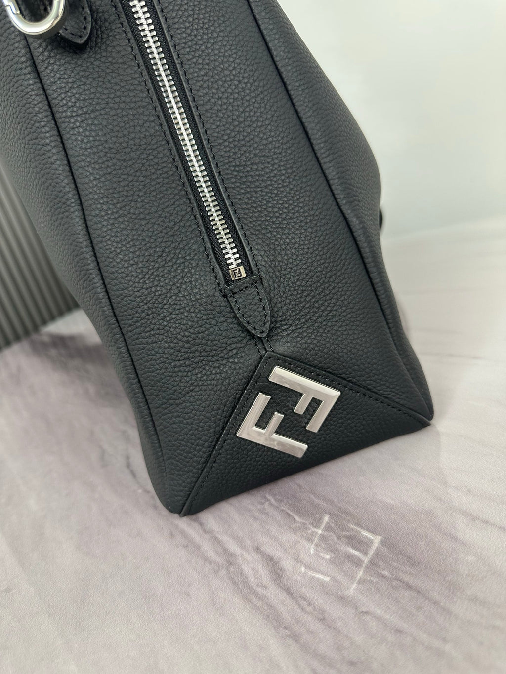 Fendi dark leather bag corner with metal zipper pull and FF logo patch