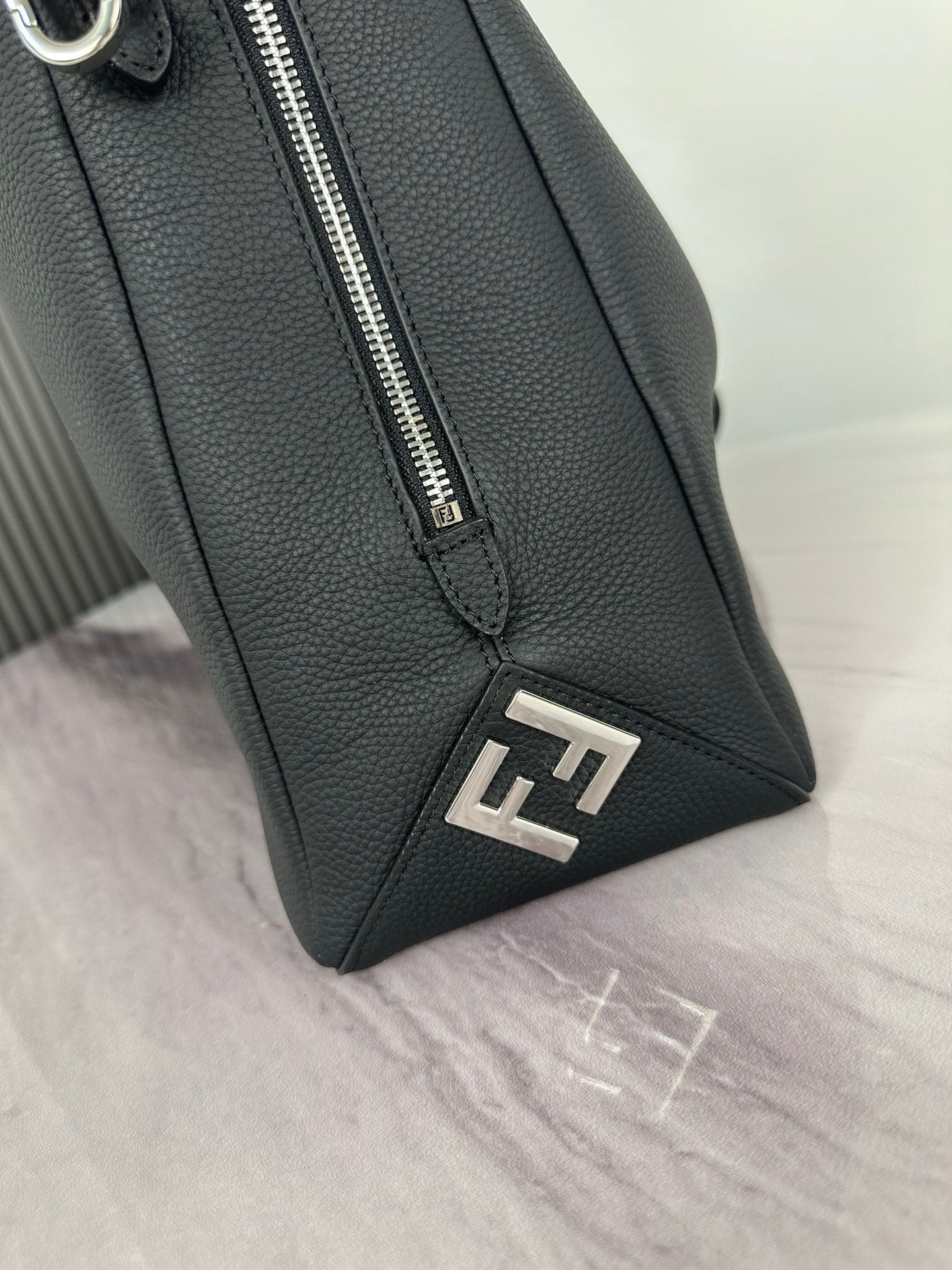 Fendi dark leather bag corner with metal zipper pull and FF logo patch