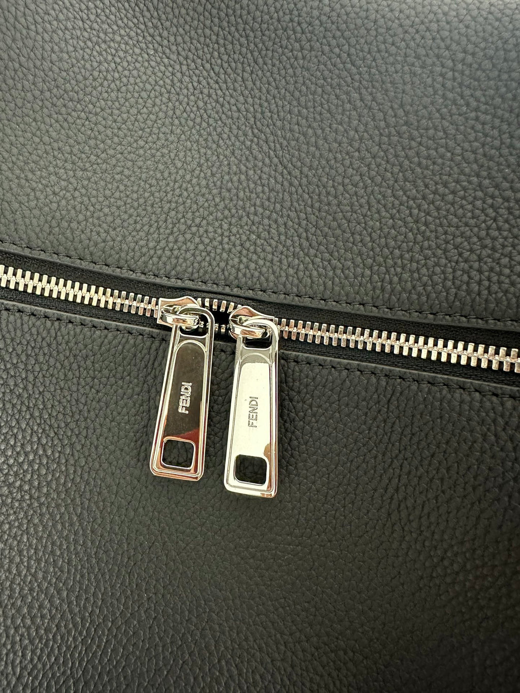 Fendi logo-engraved zipper pull tabs on dark leather bag