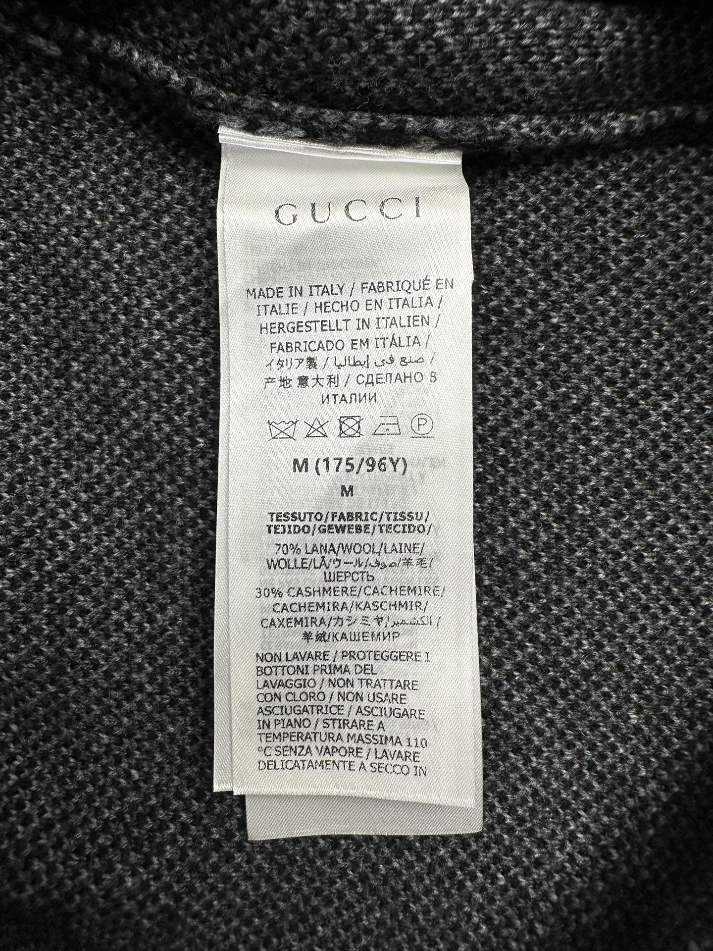 Gucci clothing care label on dark knit sweater
