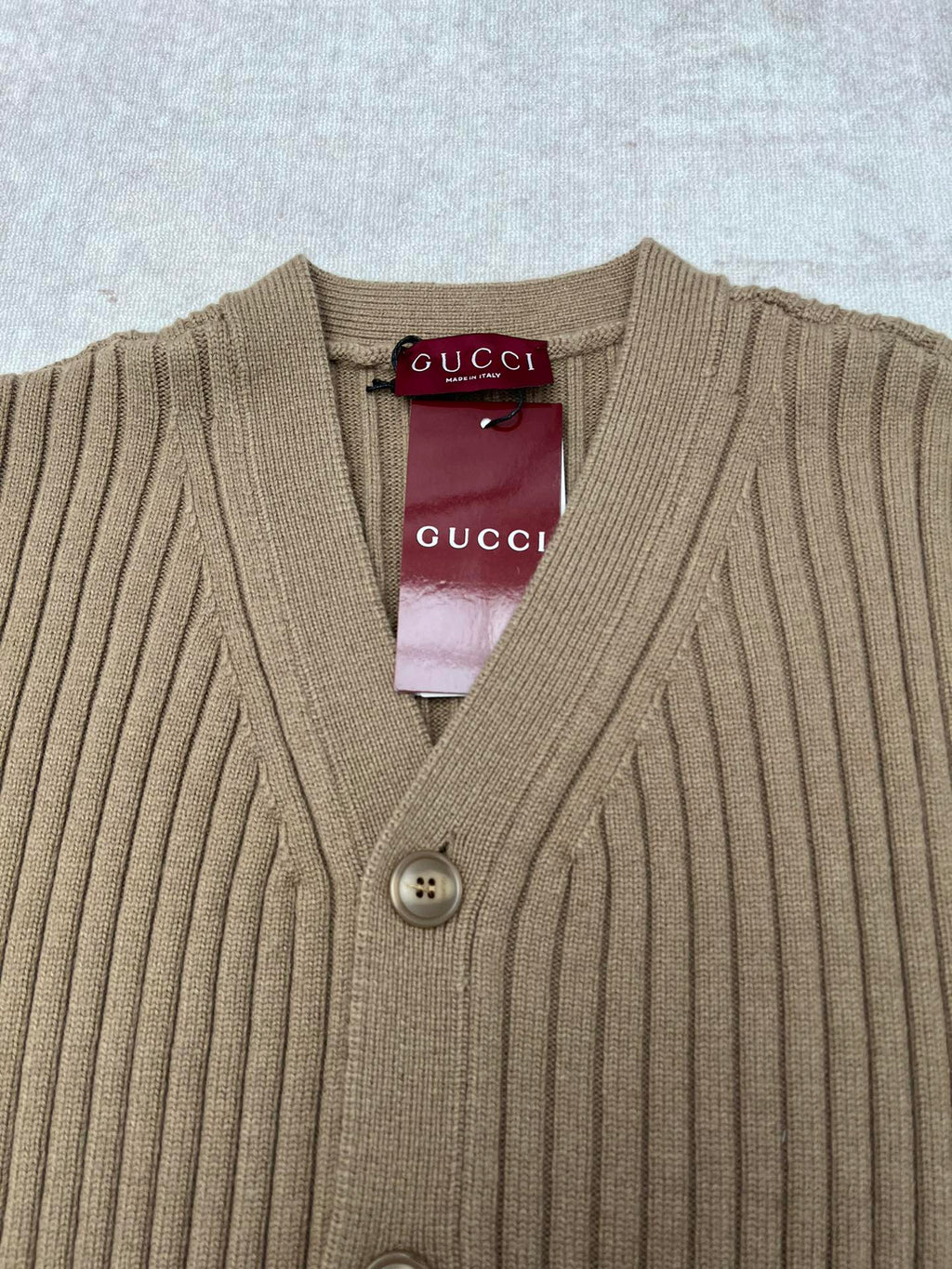 Beige rib-knit V-neck cardigan with four-button front and Gucci label at neck