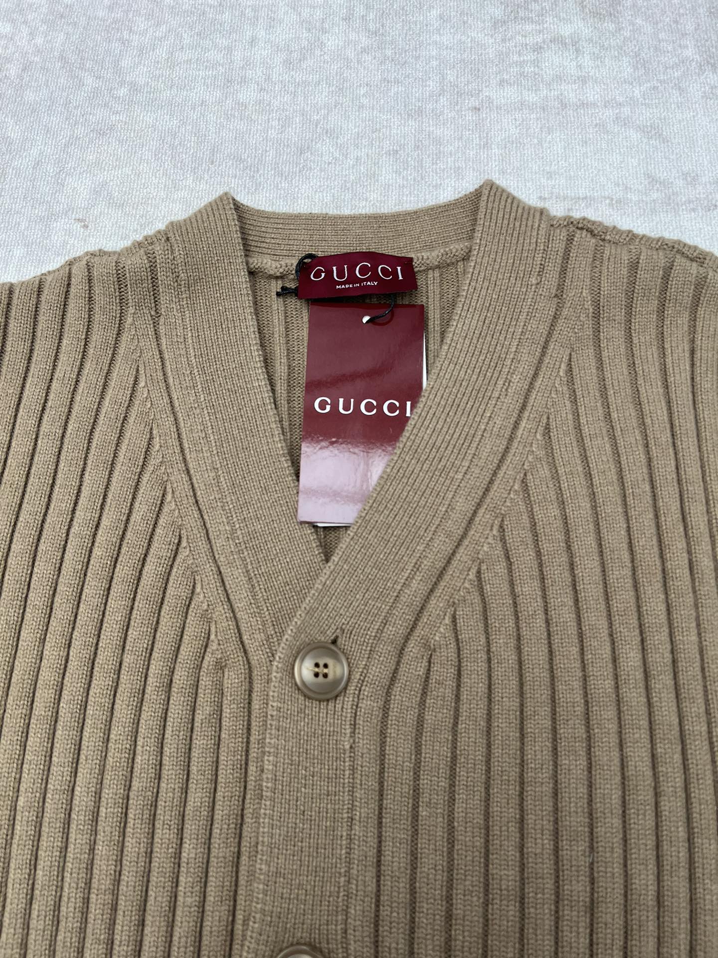Beige rib-knit V-neck cardigan with four-button front and Gucci label at neck