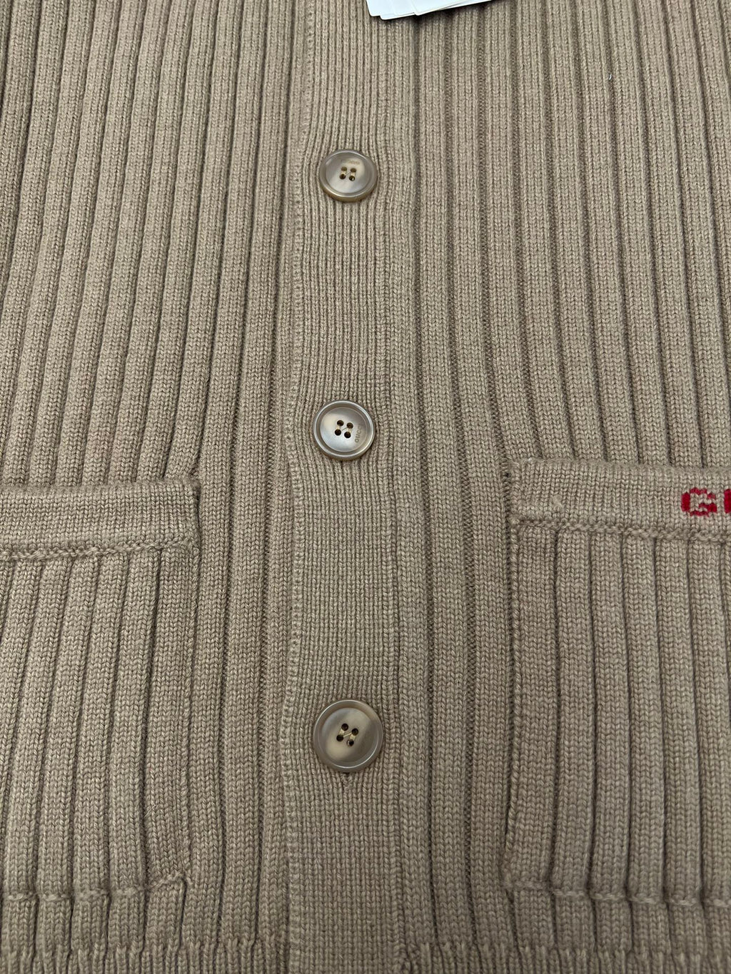 Beige cardigan front panel with three visible buttons and ribbed knit