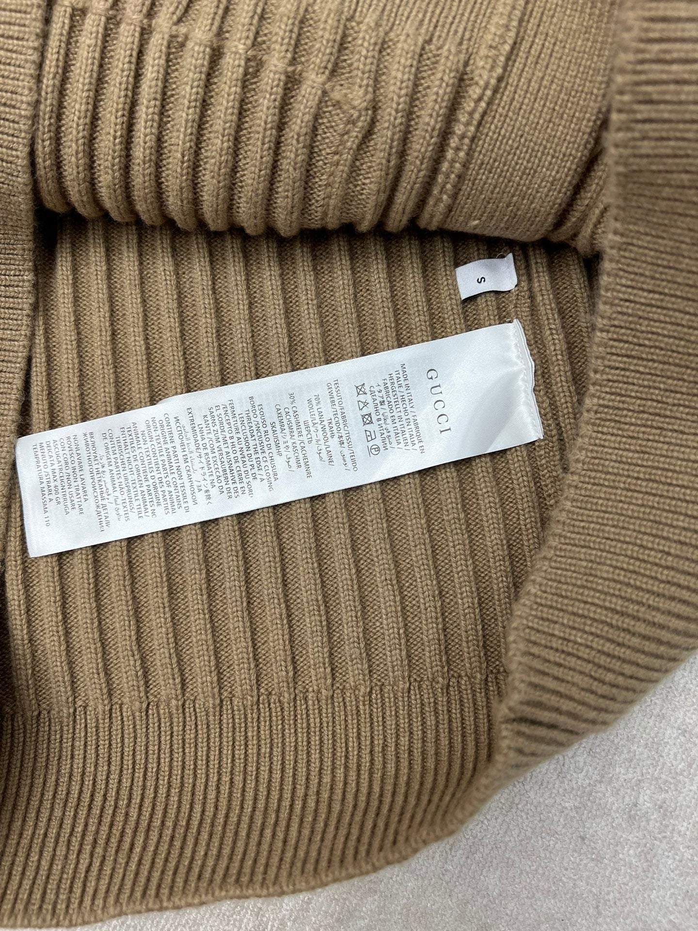 Beige rib-knit cardigan belt area with internal fabric tag label