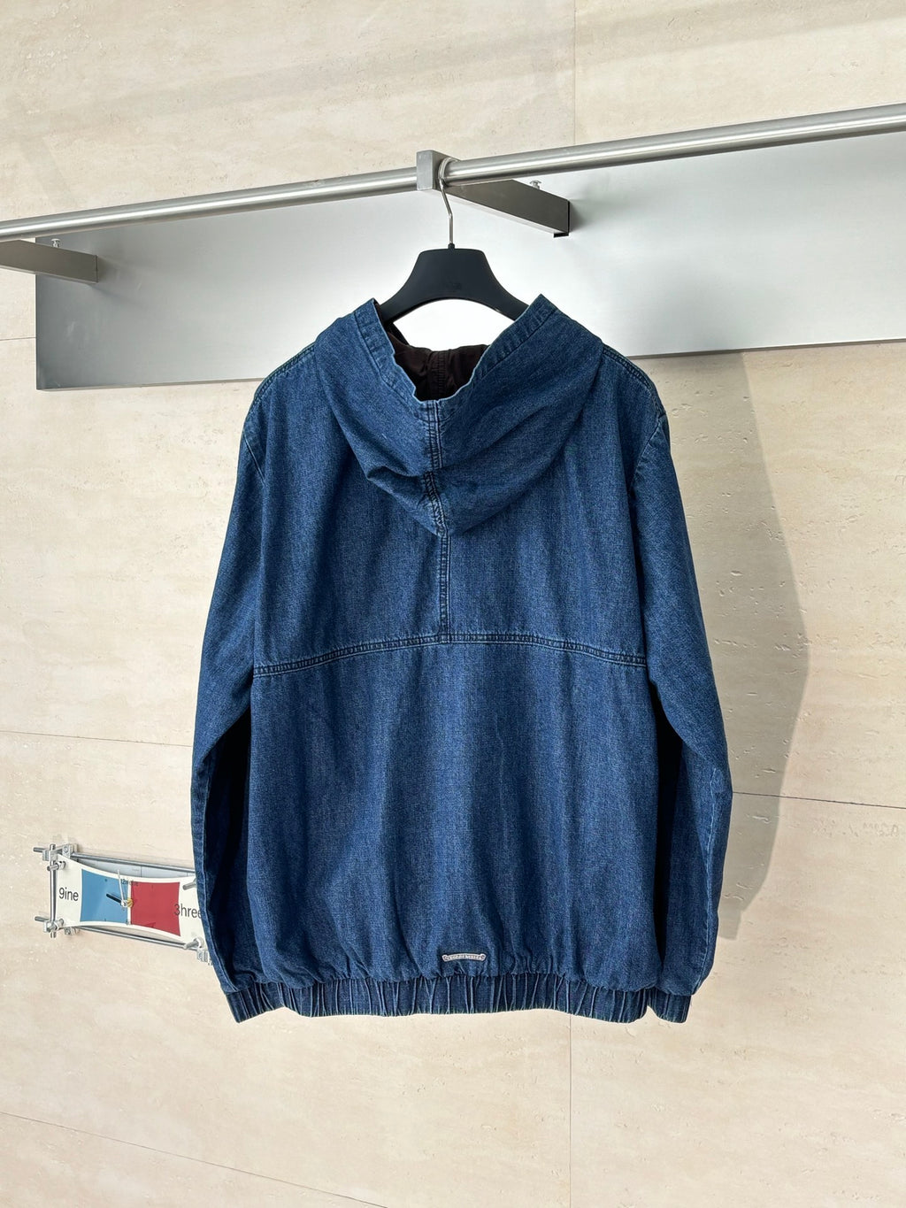 Denim hooded jacket, blue, with front half-zip and graphic emblem; hooded back view.