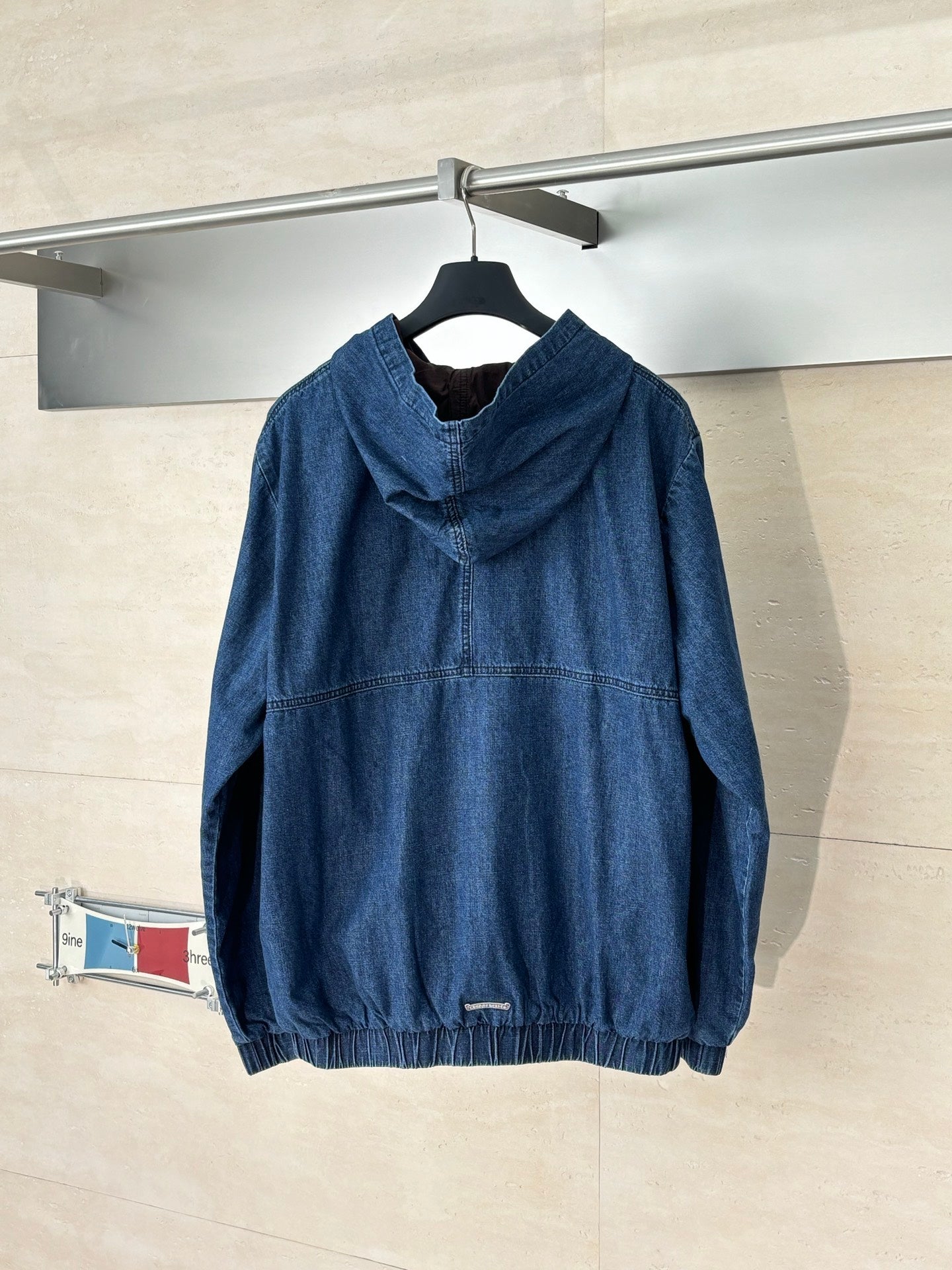 Denim hooded jacket, blue, with front half-zip and graphic emblem; hooded back view.