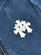 Blue denim jacket close-up with white cross-style embroidered patch on chest.