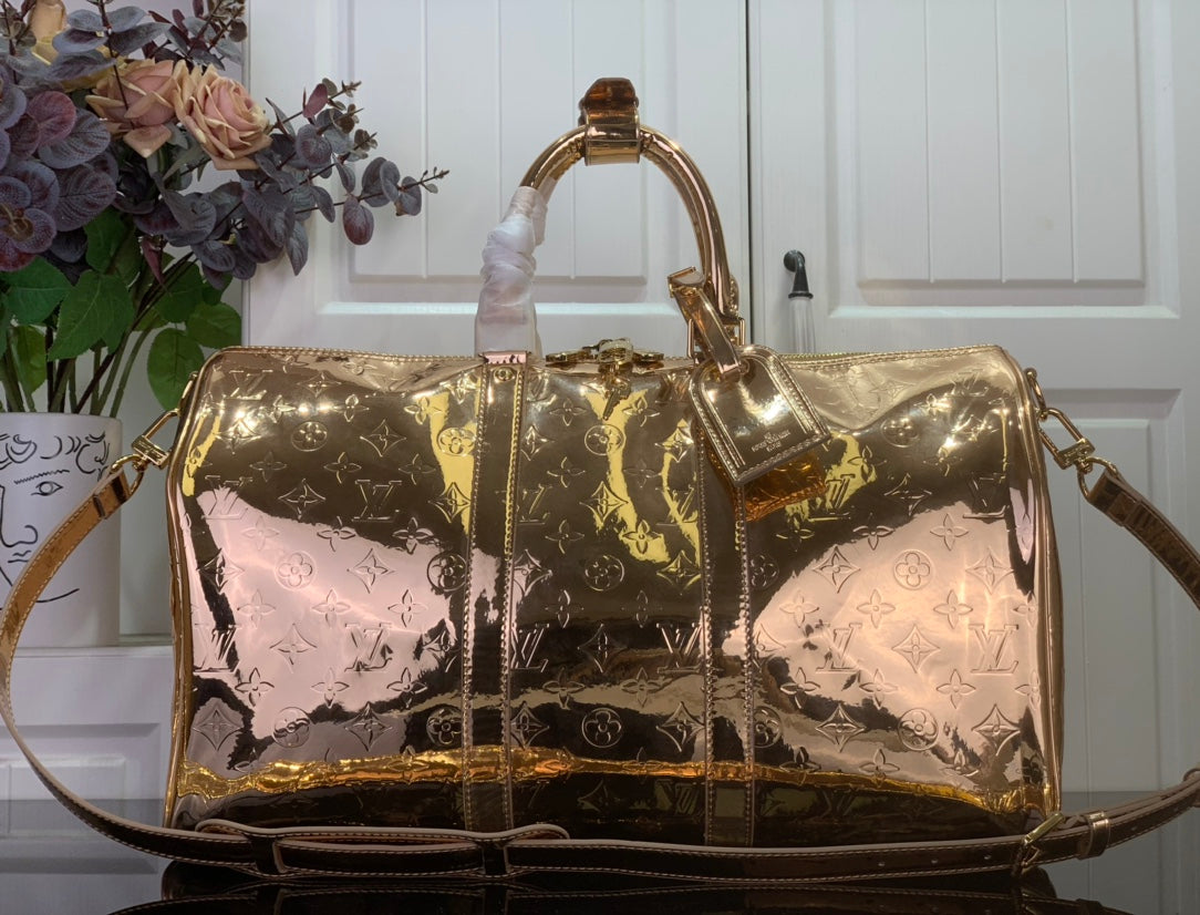 Gold monogram duffel bag with top handles and shoulder strap, shiny finish
