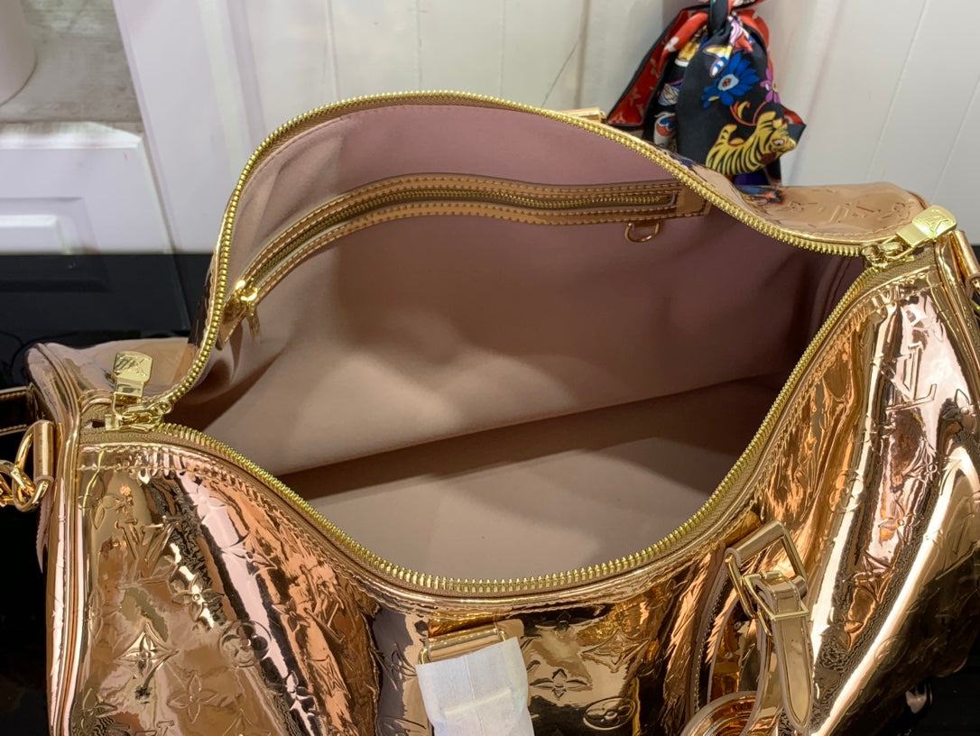 Gold monogram duffel bag open to pink interior with zip pocket
