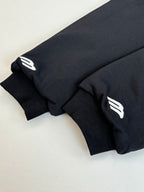 Zip-up jacket sleeves close-up with white logo patches on dark fabric