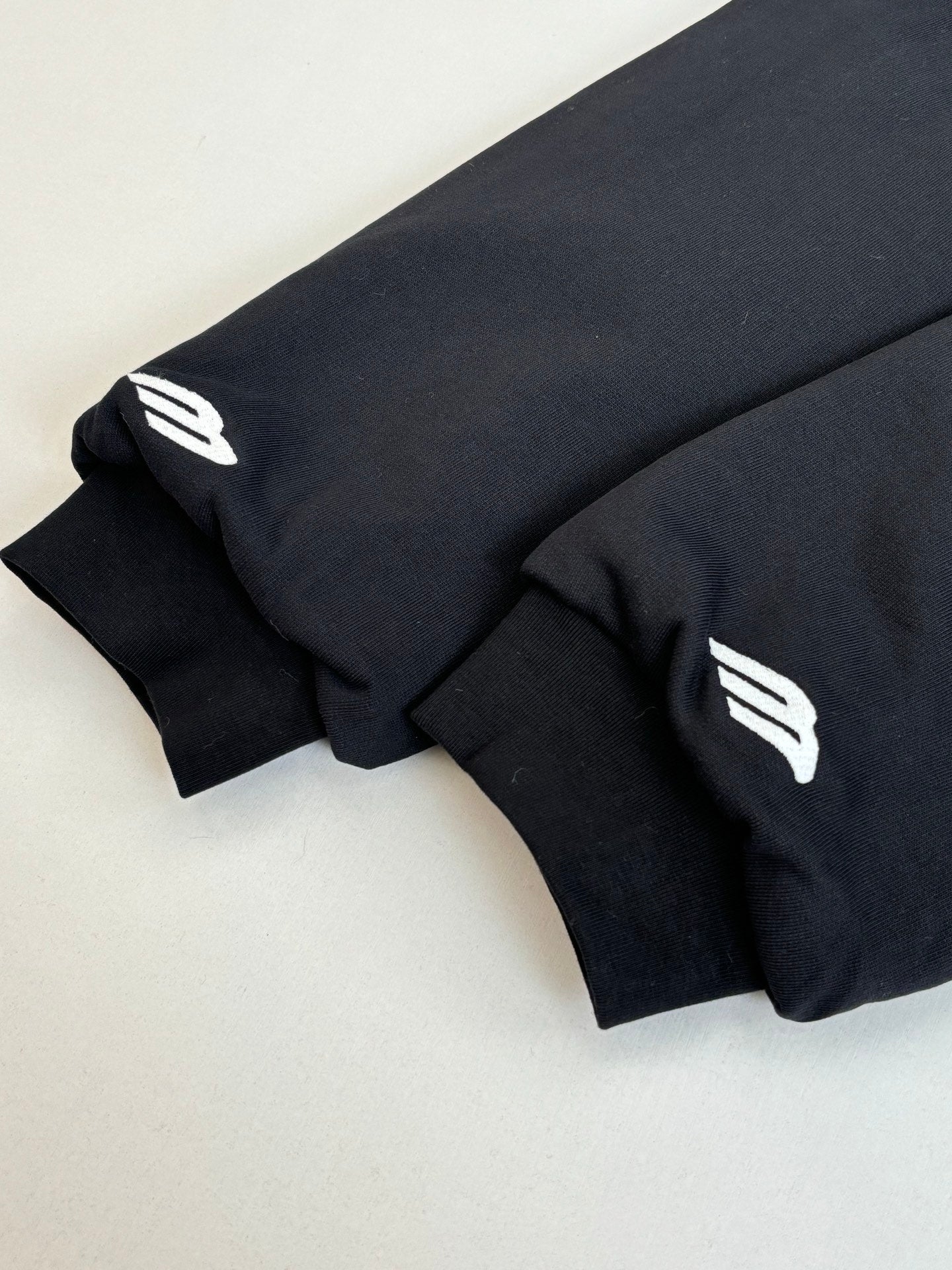 Zip-up jacket sleeves close-up with white logo patches on dark fabric