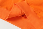 Orange long-sleeve shirt fabric close-up with stitched seam