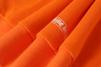 Orange long-sleeve shirt cuff with small embroidered logo
