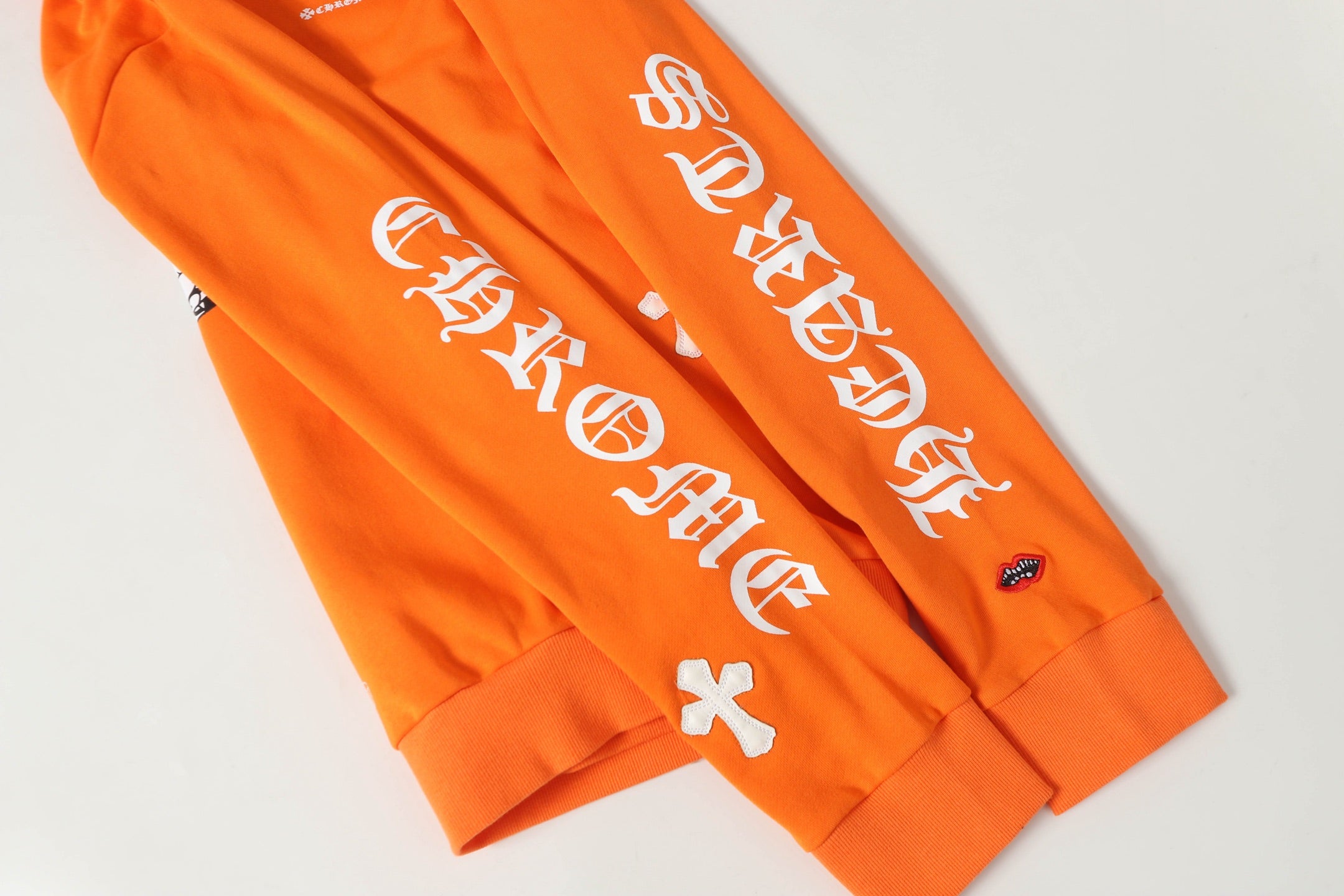 Orange hoodie sleeve with white decorative lettering graphic