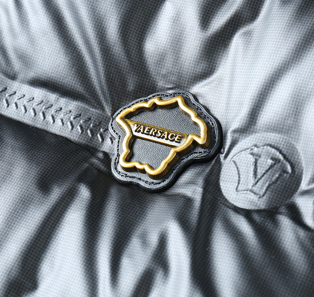 Embroidered Versace logo patch on black puffer jacket with gold trim