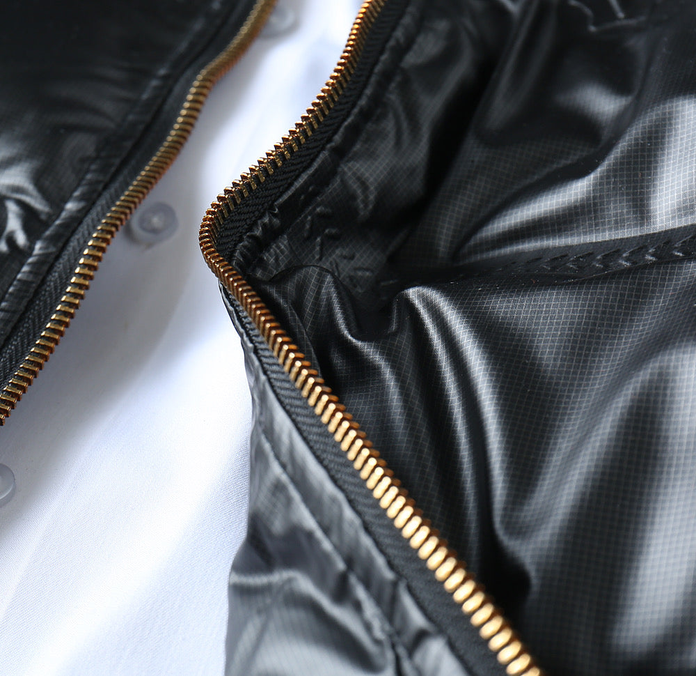 Black puffer jacket zipper seam with gold piping detail