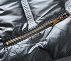 Black puffer jacket with gold-tone zipper and engraved pull tab