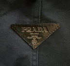 Prada logo patch on dark fabric, triangular emblem with gold lettering