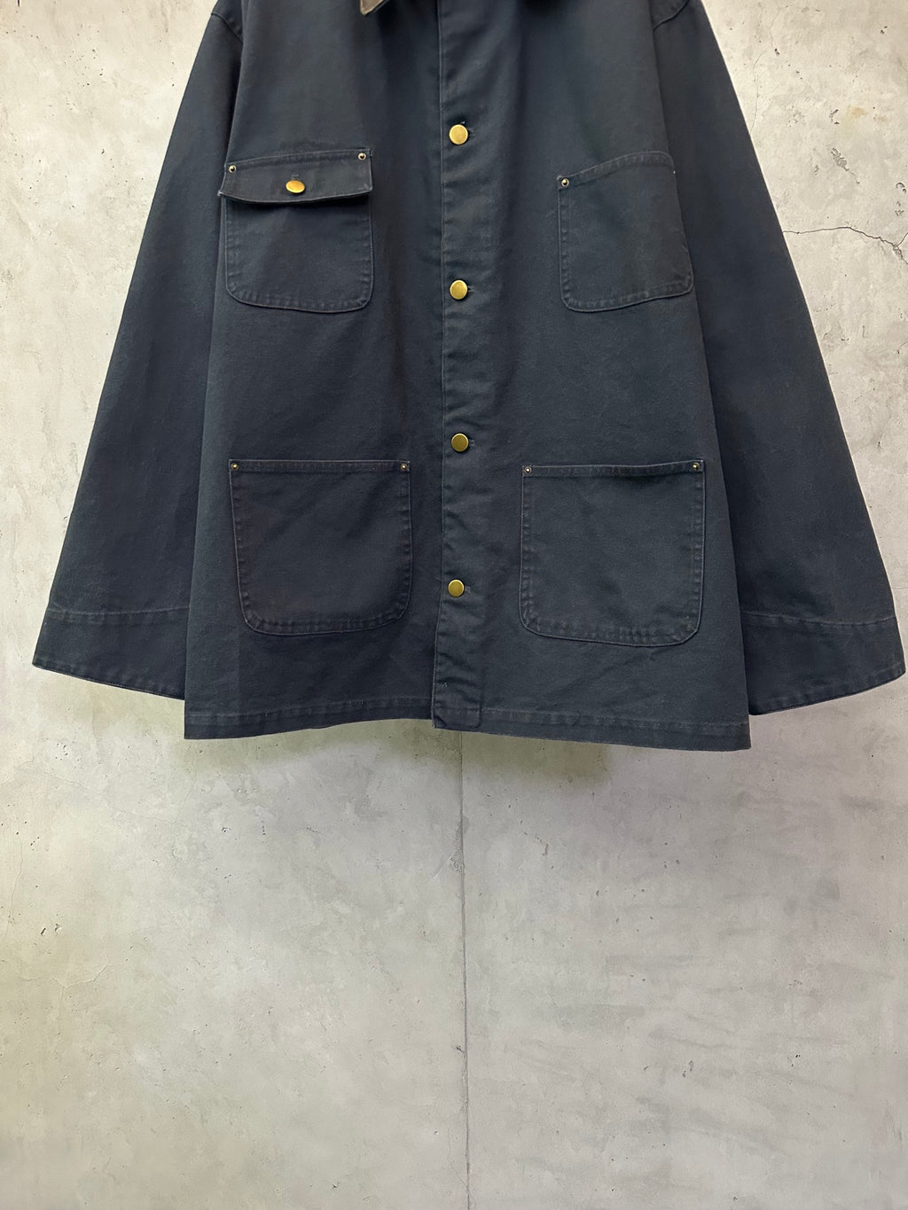 Navy long jacket with button front, flap chest pockets, and flap sleeve cuffs