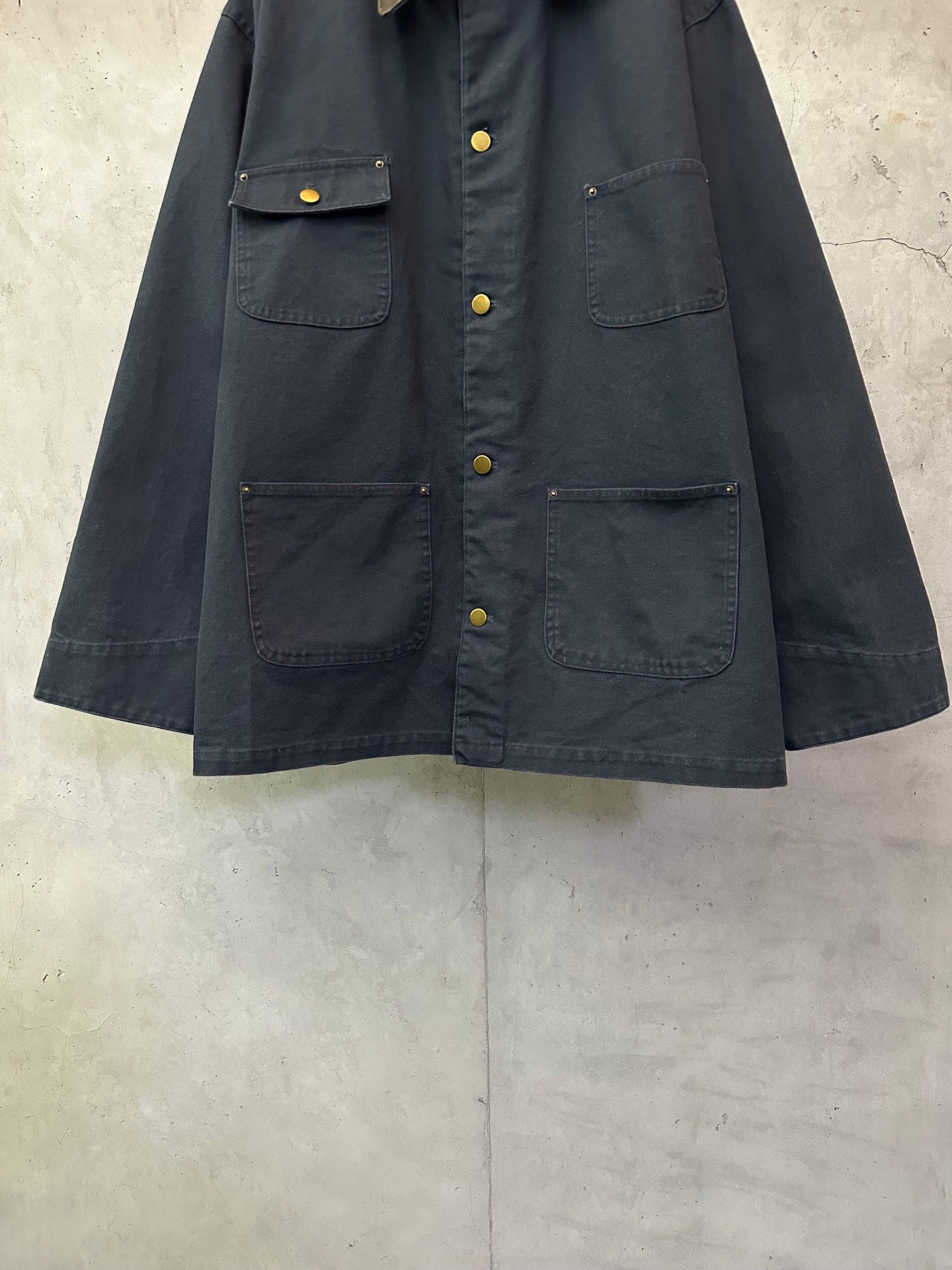 Navy long jacket with button front, flap chest pockets, and flap sleeve cuffs