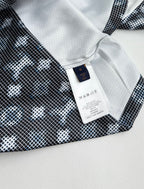 Long-sleeve top label at collar with white tag and dark geometric print fabric