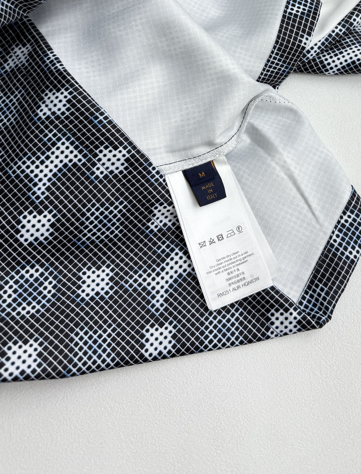 Long-sleeve top label at collar with white tag and dark geometric print fabric