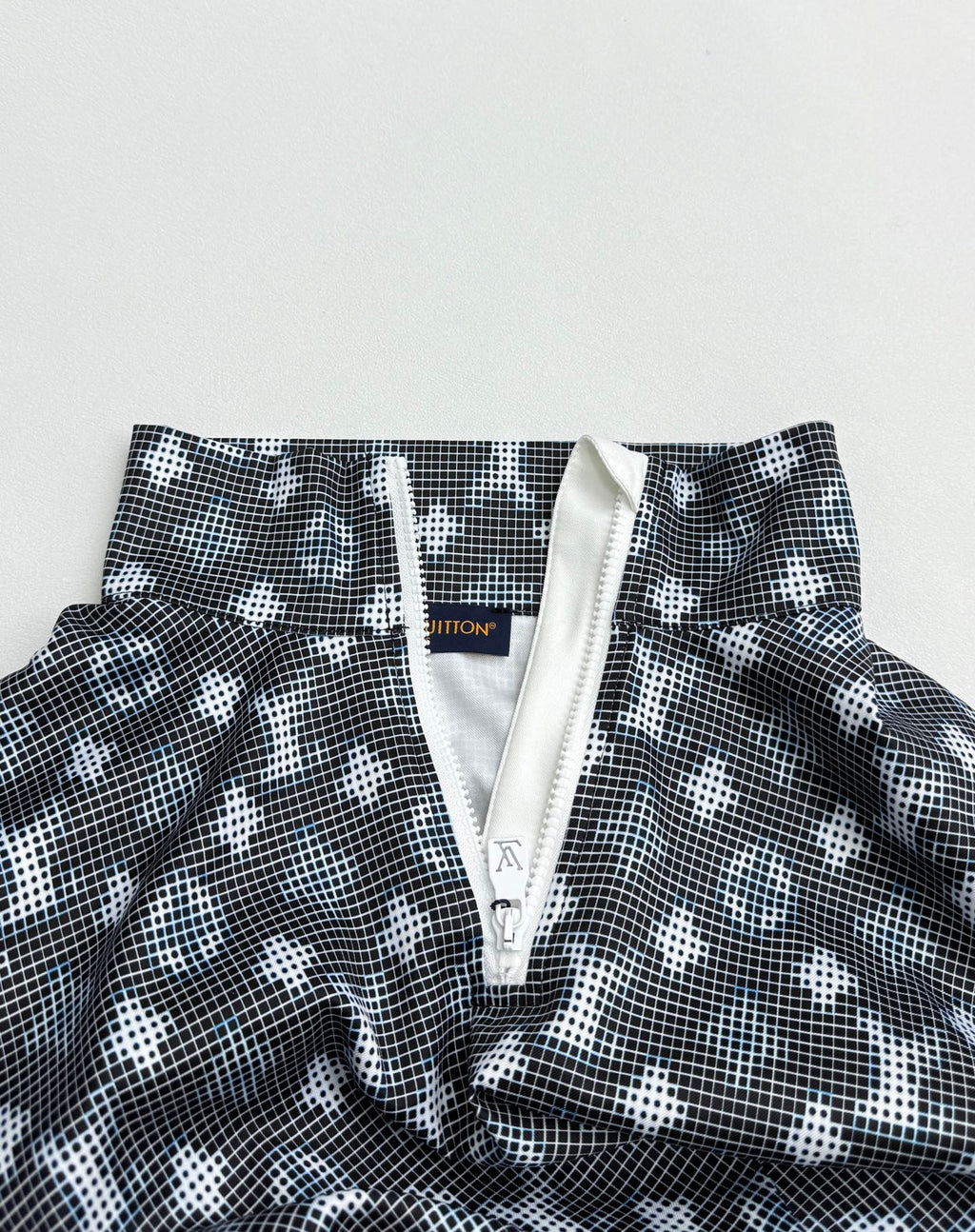 Long-sleeve top close-up of front placket with zipper pull and dark geometric print