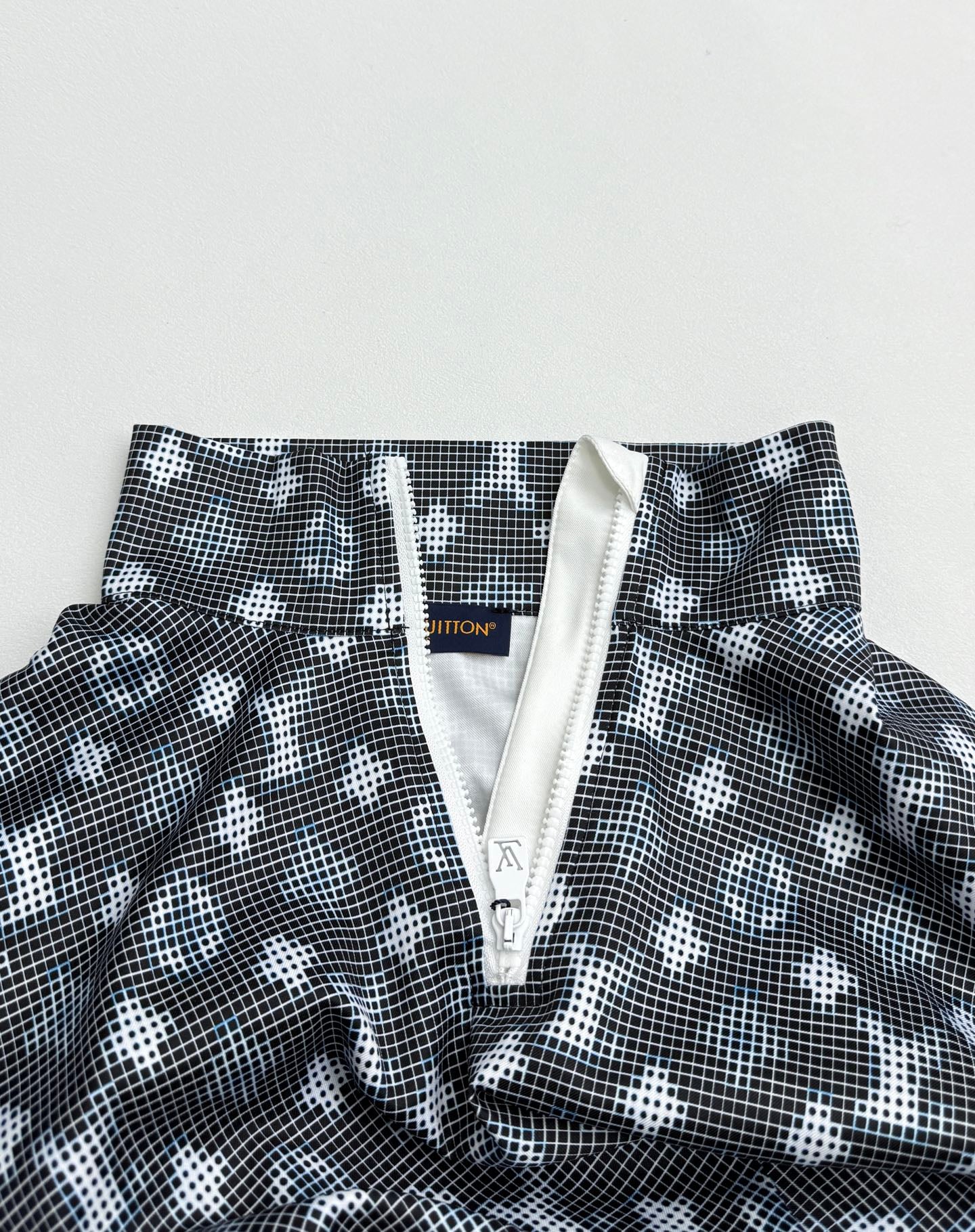Long-sleeve top close-up of front placket with zipper pull and dark geometric print
