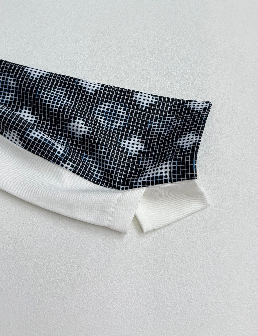 Long-sleeve cuff detail with dark geometric print and white band at the hem