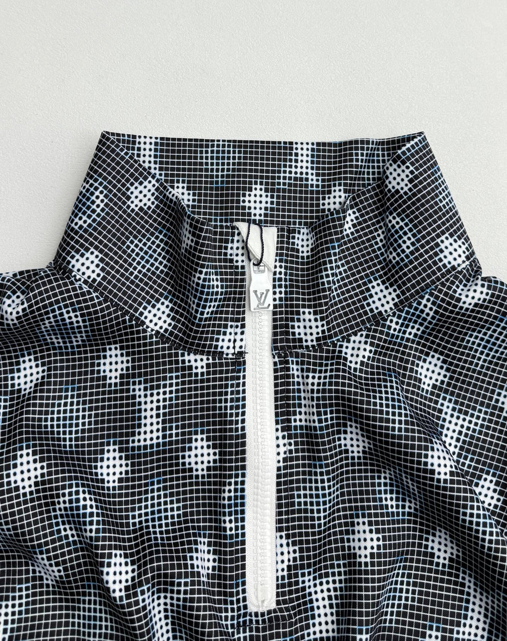 Long-sleeve top neckline detail with dark geometric print and central zip placket