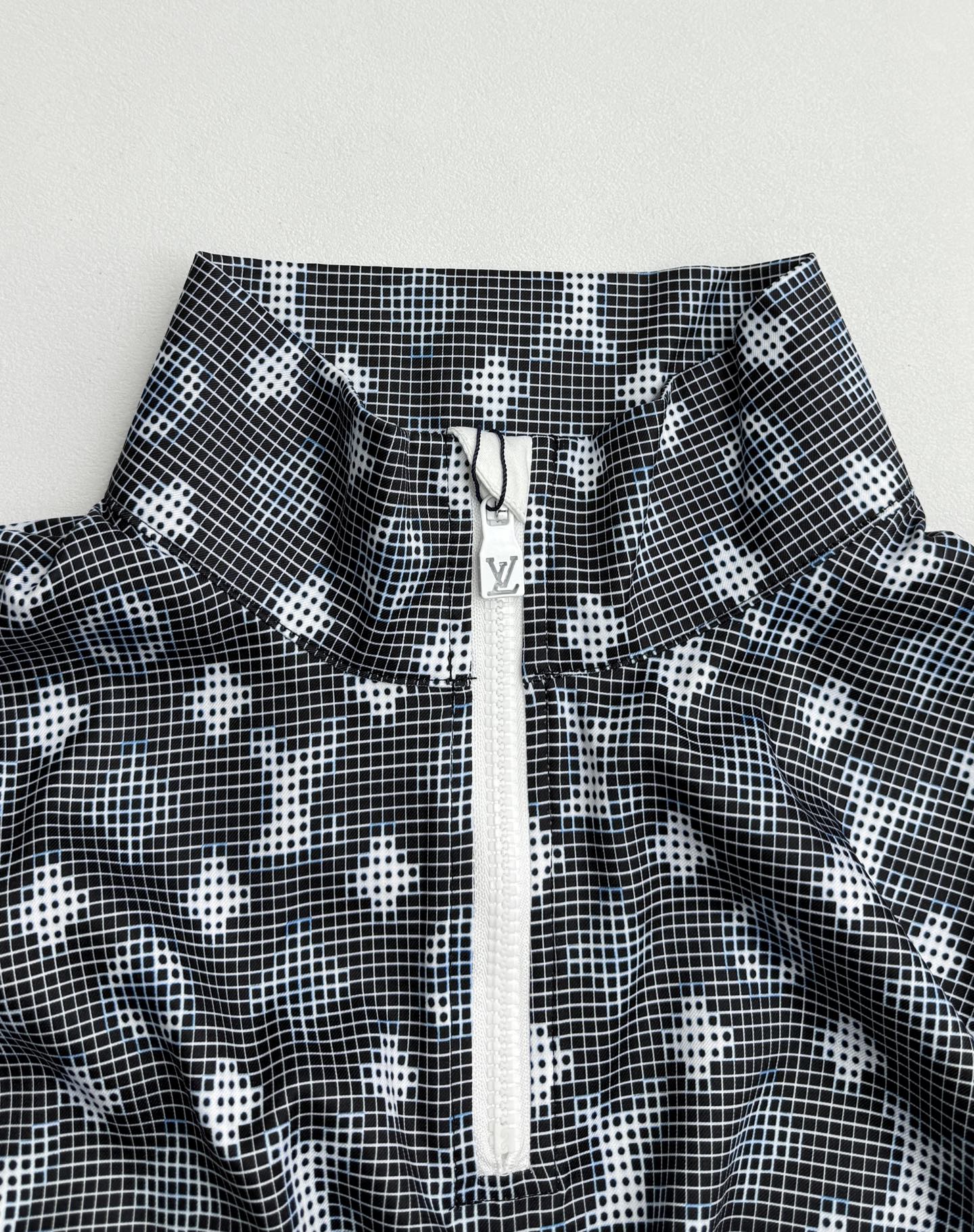 Long-sleeve top neckline detail with dark geometric print and central zip placket