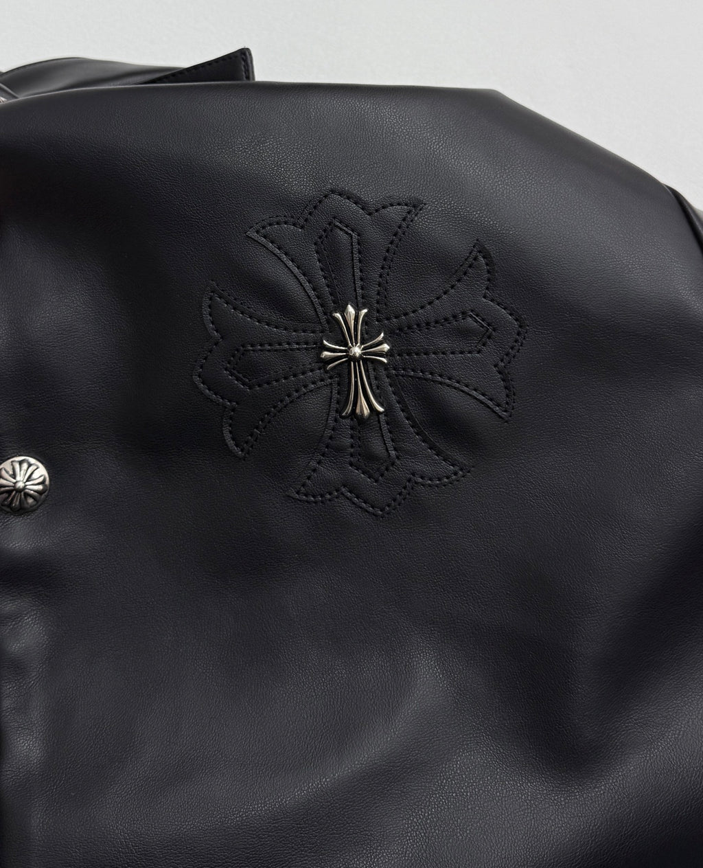 Black leather-look jacket with embroidered floral cross patch on shoulder