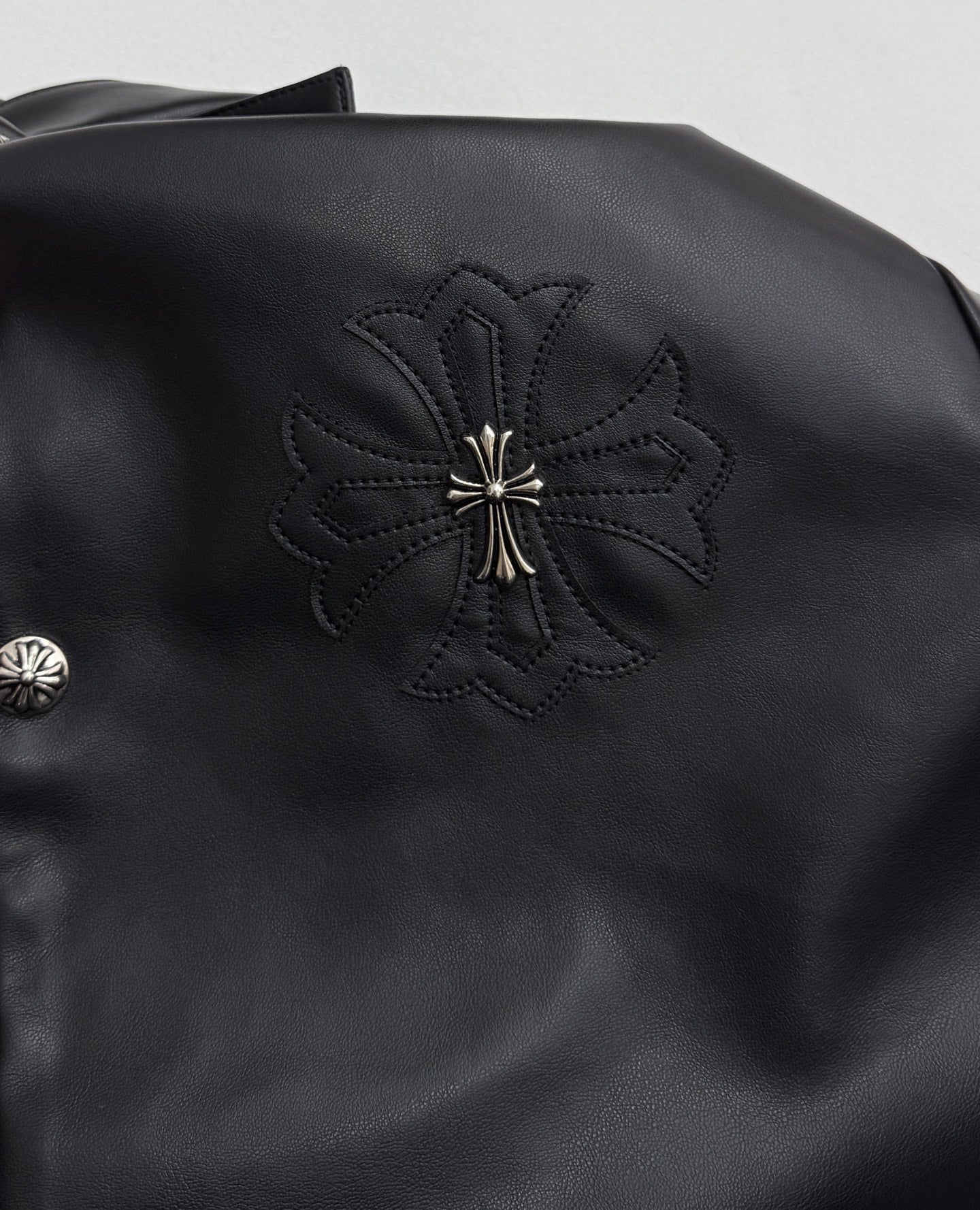 Black leather-look jacket with embroidered floral cross patch on shoulder